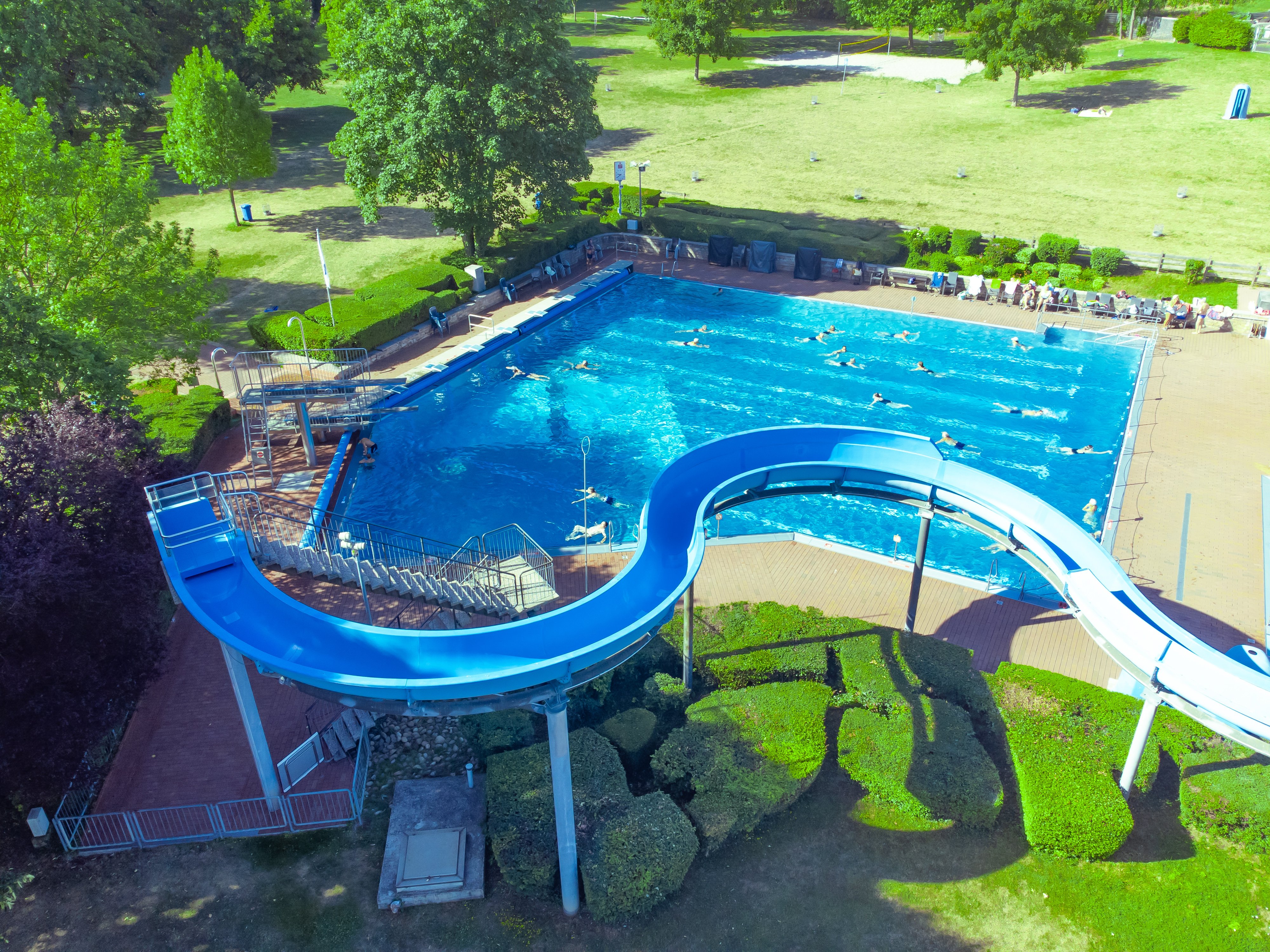Vor dem Schwimmerbecken ist die blaue Wasserrutsche des Alzeyer Wartbegbads zu sehen.