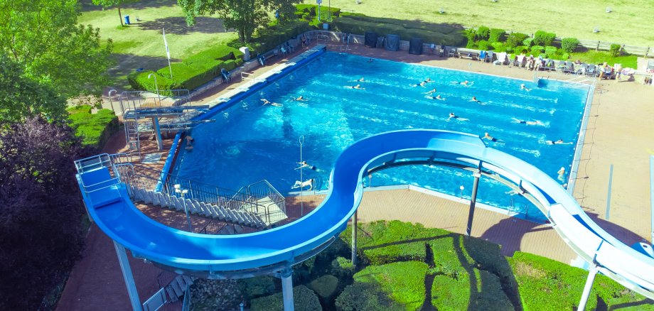 Vor dem Schwimmerbecken ist die blaue Wasserrutsche des Alzeyer Wartbegbads zu sehen.