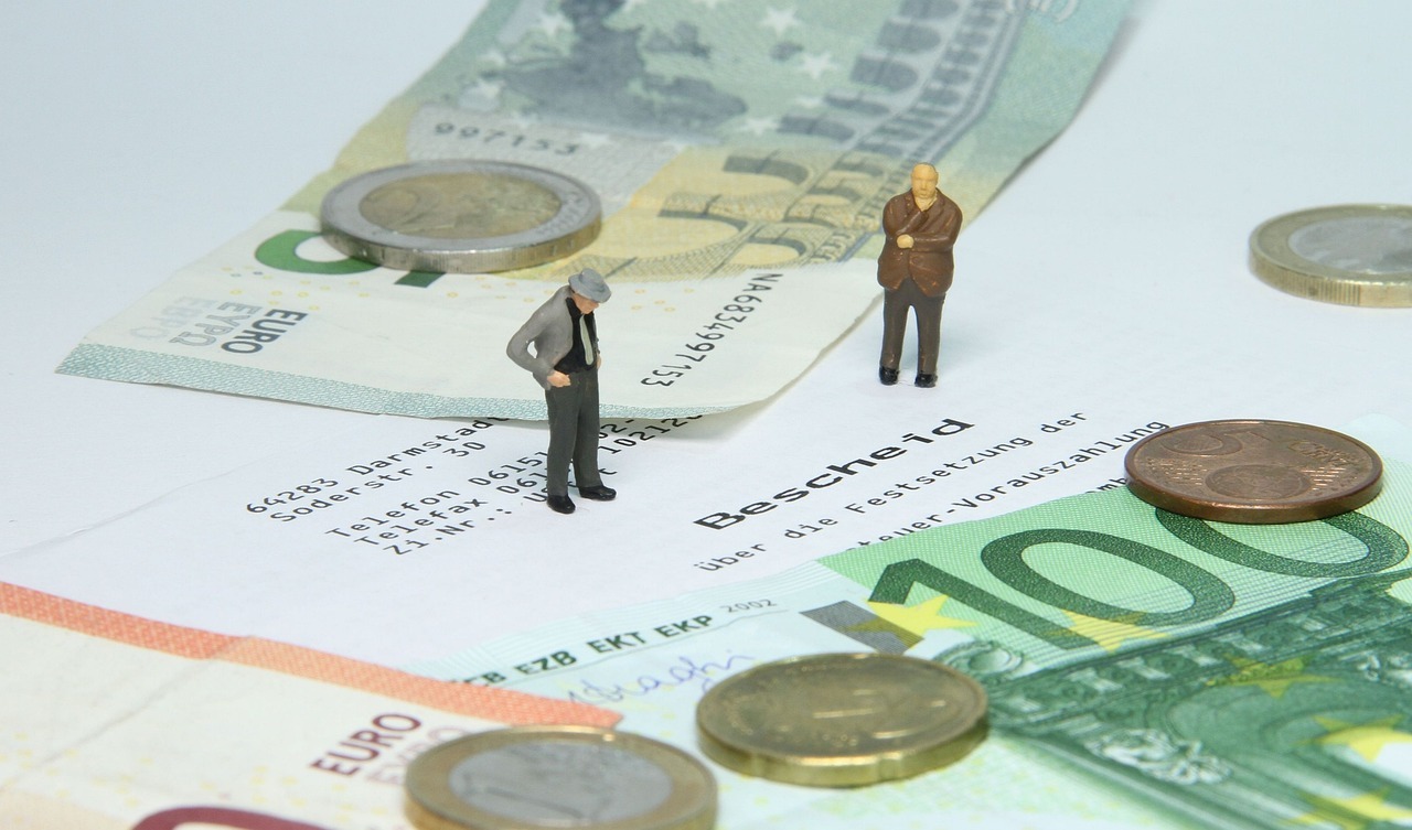 2 Menschliche mini Figuren stehen auf einem Bescheid und außen liegt Geld