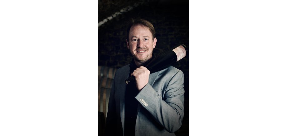 Andreas Wagner mit einer Weinflasche auf der Schulter