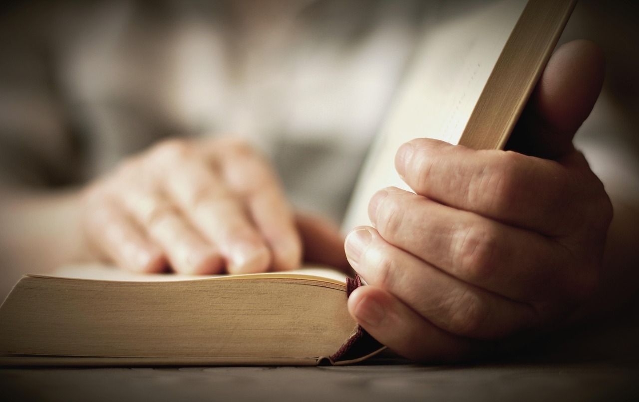 eine Person mit ein Buch liest aber nur die Hände zu sehen sind