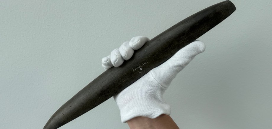 ein weißer Handschuh angezogen und in der Hand ein etwas spitzer Gegenstand mit Armsheim eingraviert