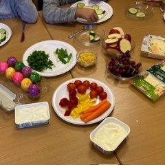 Auf dem Bild sieht man einen Tisch, gedeckt mit Obst, Gemüse, Wurst, Käse und Aufstrichen.