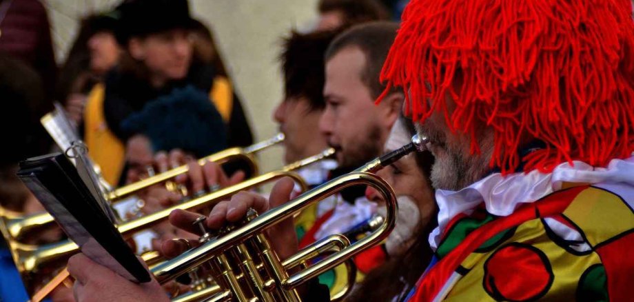 Man sieht Blasmusiker des Fastnachtsumzuges als Clown verkleidet die gemeinsam musizieren.