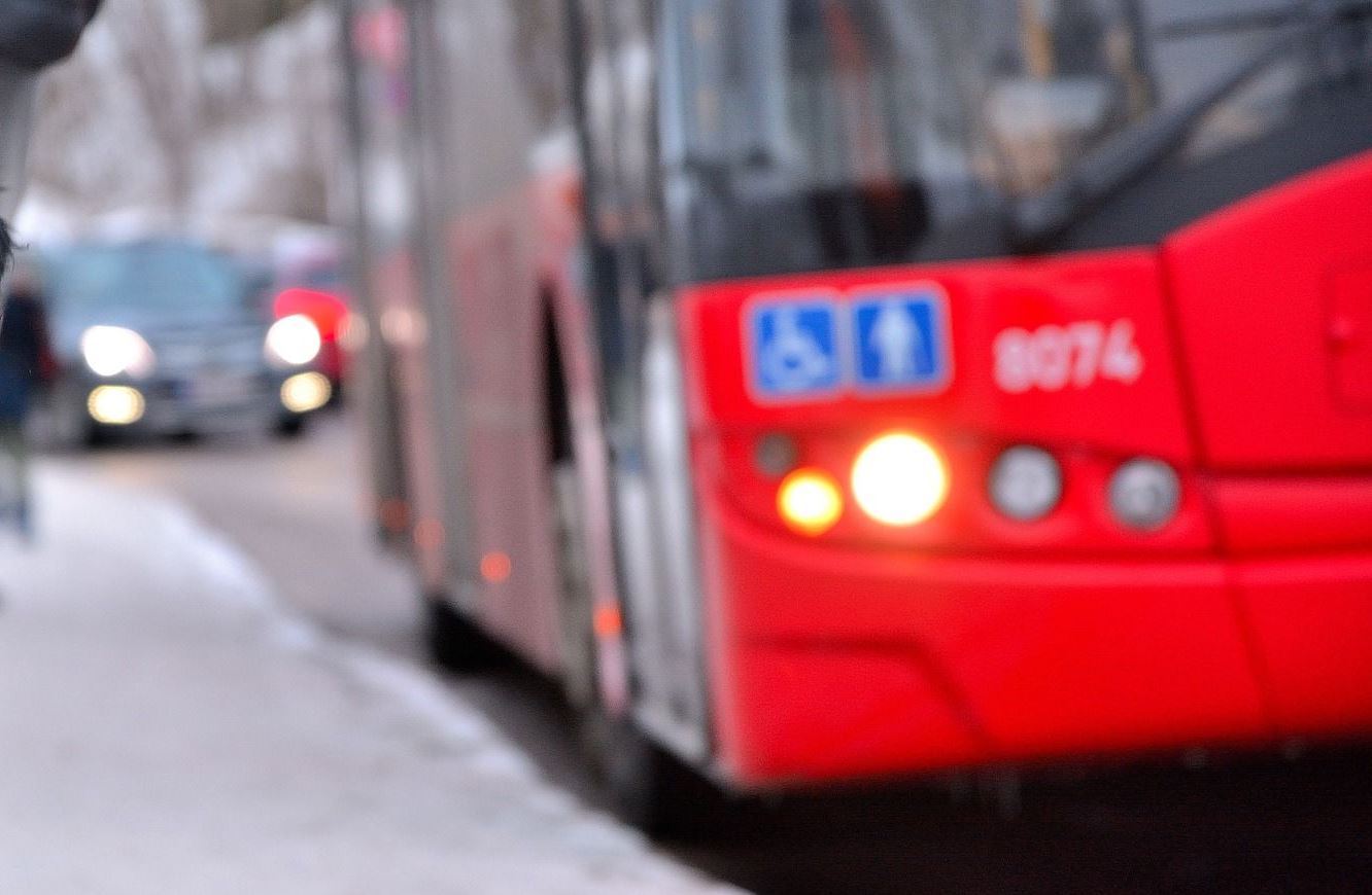 Man sieht auf dem Bild einen Ausschnitt eines Busses der auf der Straße fährt.