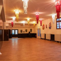 Ein Bild von der Stadthalle innen man sieht mehrere bunte Kronläuchter und etwas Fastnachtsdeko an den Wänden (Masken und Clowns).