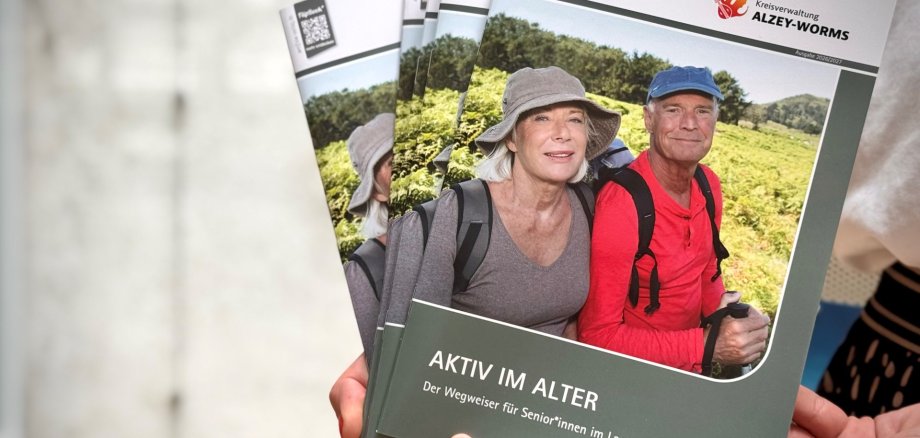 zwei ältere Personen im Wander-Outfit sind auf dem Cover eines Prospekts zu sehen, beide schauen glücklich in die Kamera