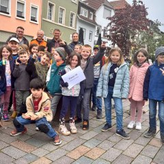 Eine Gruppe von Kindern steht auf einem Platz undalle lachen in die Kamera.
