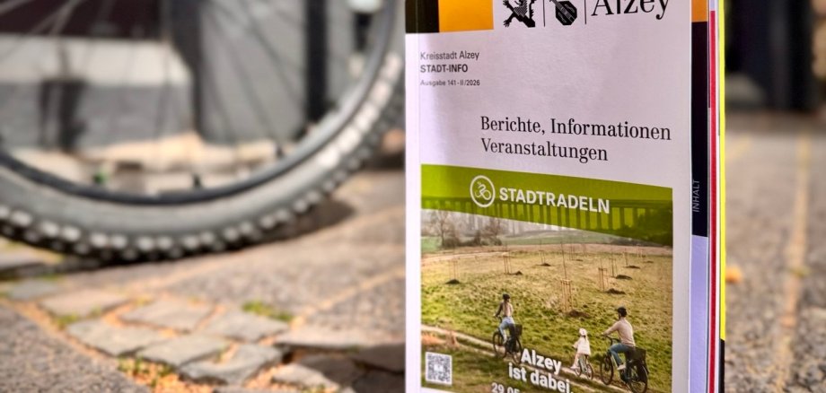 die neuste Ausgabe der Stadtinfo mit der Stadtradelaktion auf dem Titelbild steht auf dem Boden vor einem Fahrrad