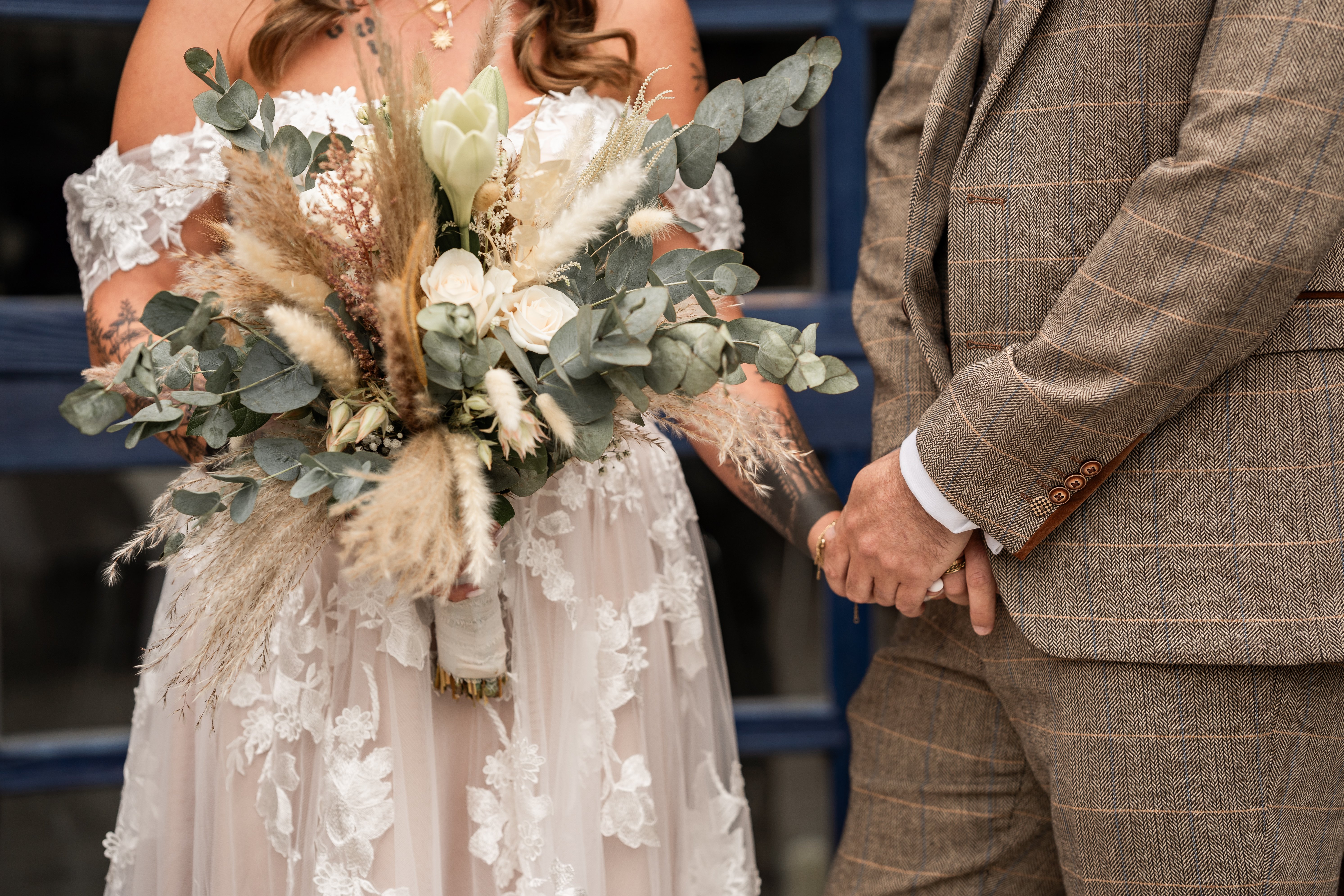 Braut und Bräutigam Hand in Hand mit Brautstrauß