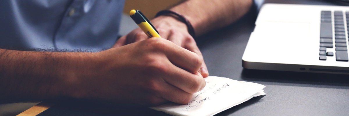 Person schreibt auf ein Blatt