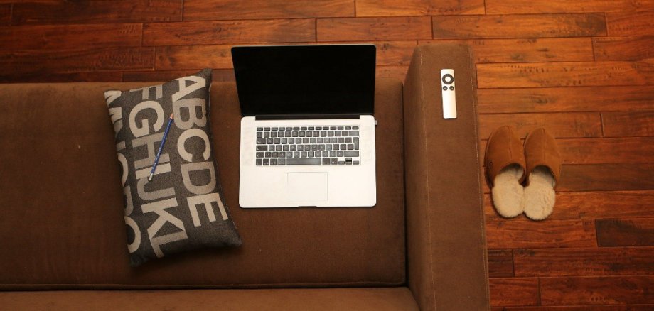Laptop auf der Couch mit Fernbedienung 
