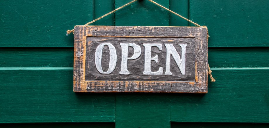 "Open"-Schild an einer grünen Tür