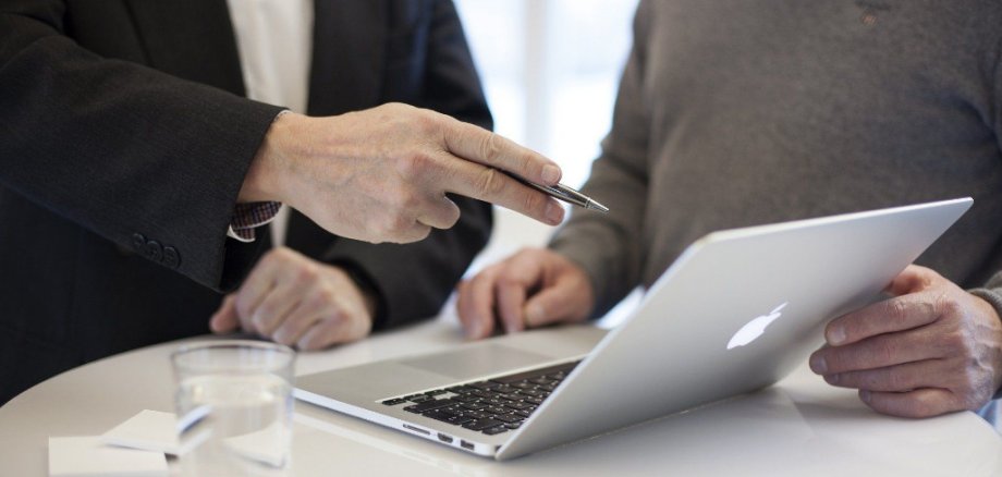 Person zeigt mit einem Stift auf einen laptop