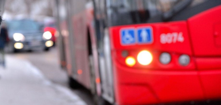 roter Bus hält an einer Bushaltestelle