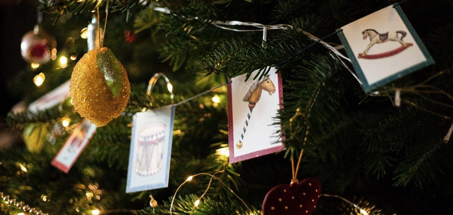 Ein geschmückter Weihnachtsbaum mit figuren und einer Lichterkette und Girlande.