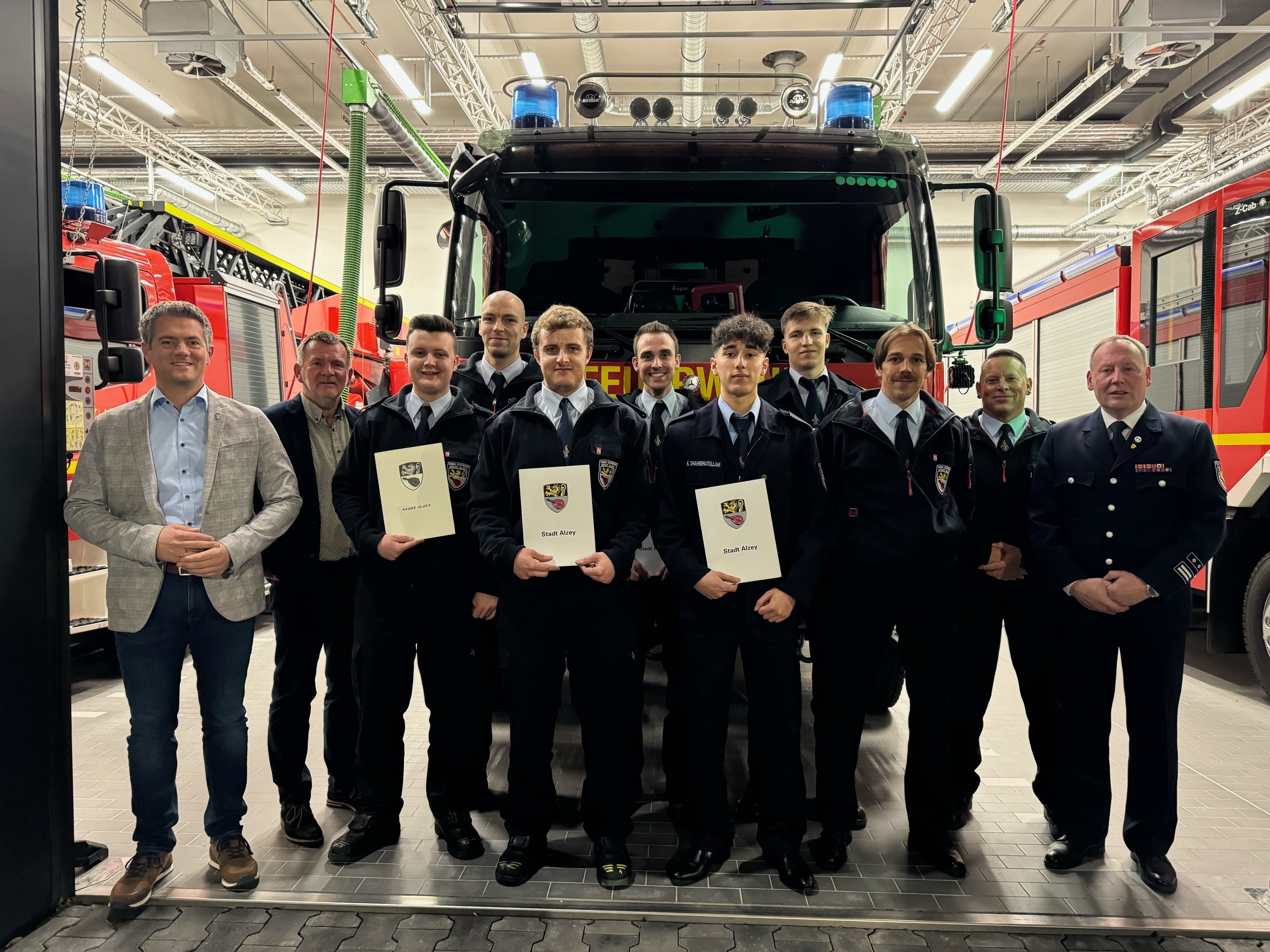 Eine Gruppe von Feuerwehrmännern steht mit Urkunden in der Hand vor einem Feuerwehrauto.