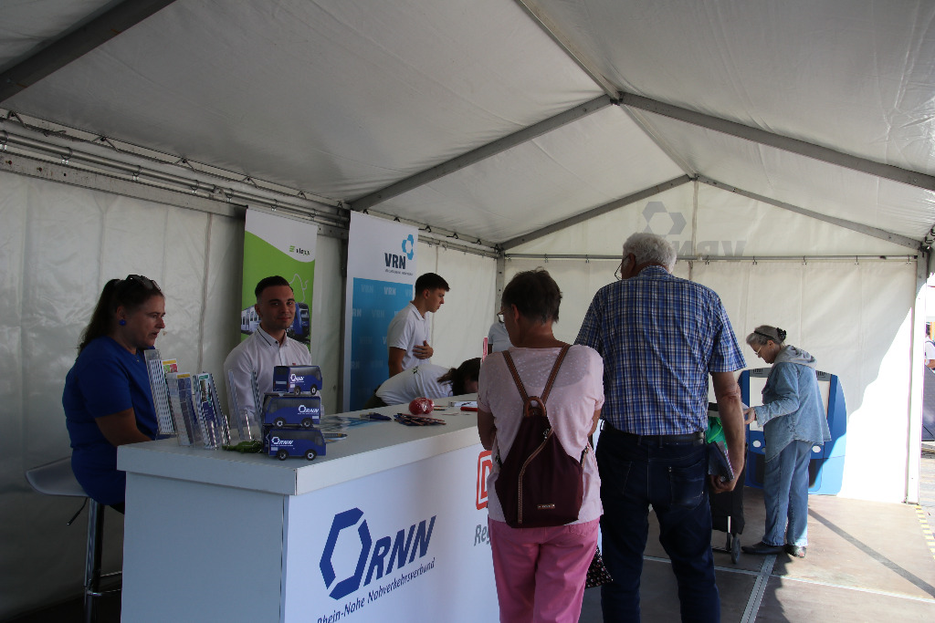 Viele Menschen informieren sich an einem Stand eines Busunternehmens