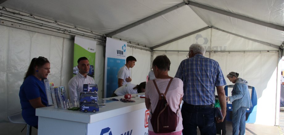 Viele Menschen informieren sich an einem Stand eines Busunternehmens