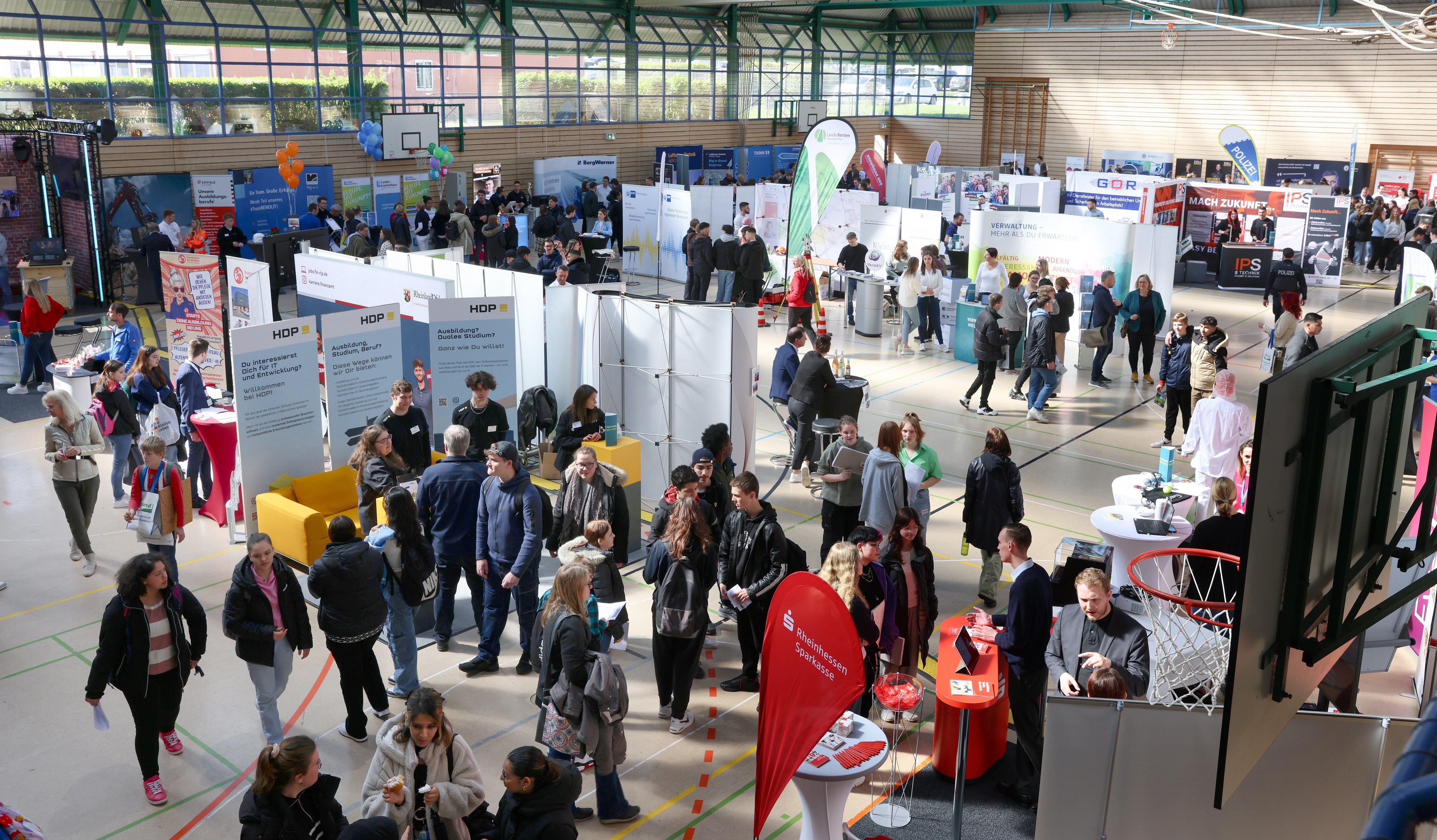 In einer Halle tummeln sich viele junge Menschen zwischen den Infoständen.