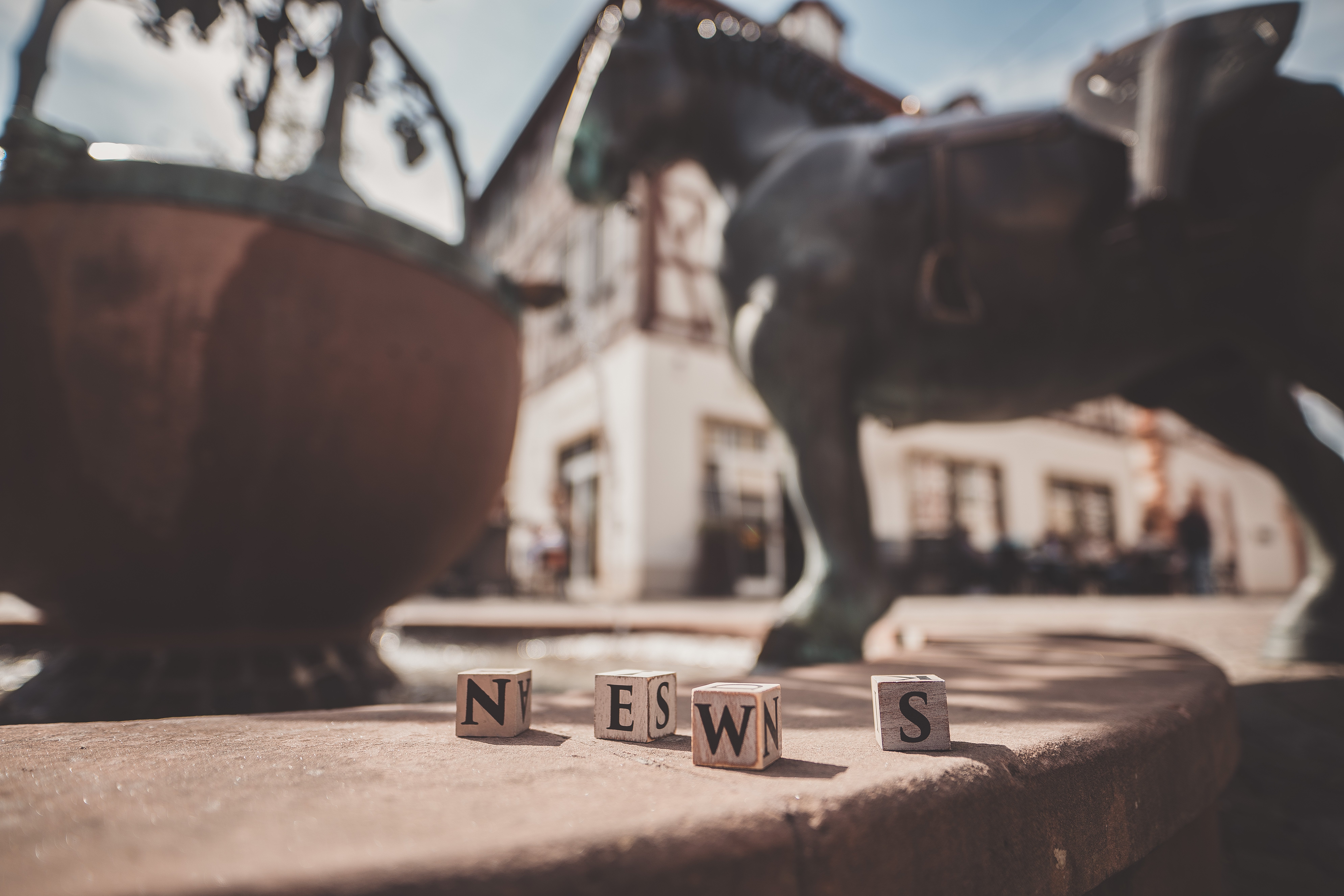 Vier Holzklötze formen das Wort "News" auf dem Rand des Roßmarktbrunnens