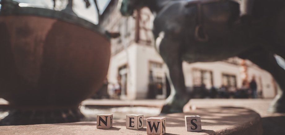 Vier Holzklötze formen das Wort "News" auf dem Rand des Roßmarktbrunnens