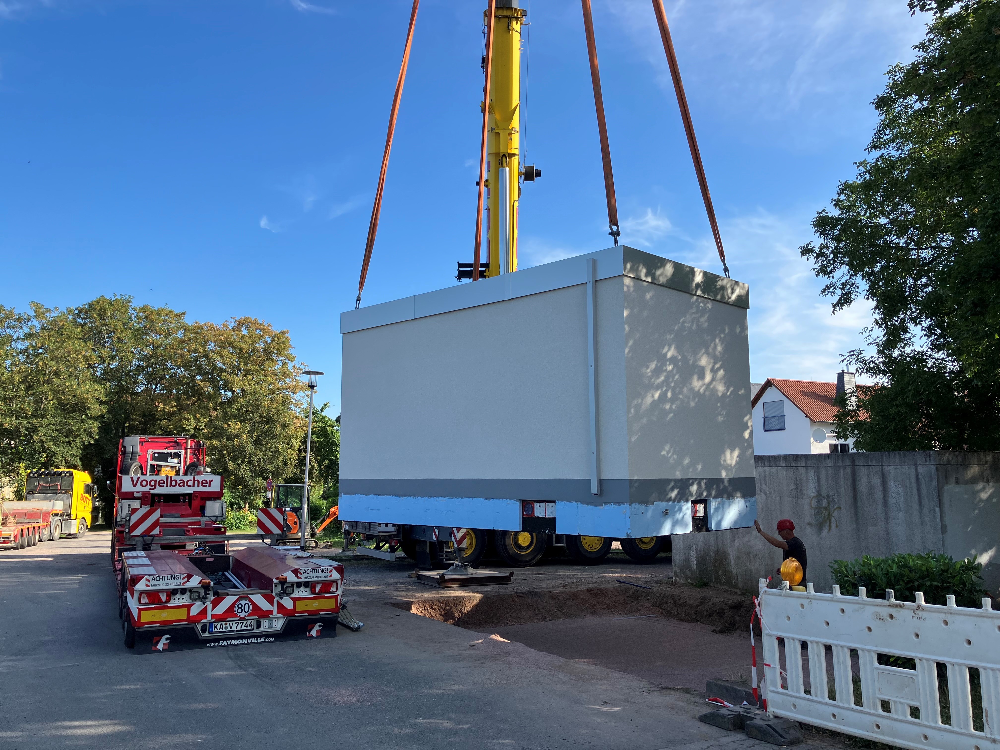 Ein großer grauer Container wird mit einem riesigen Kran in einer Grube abgesetzt.