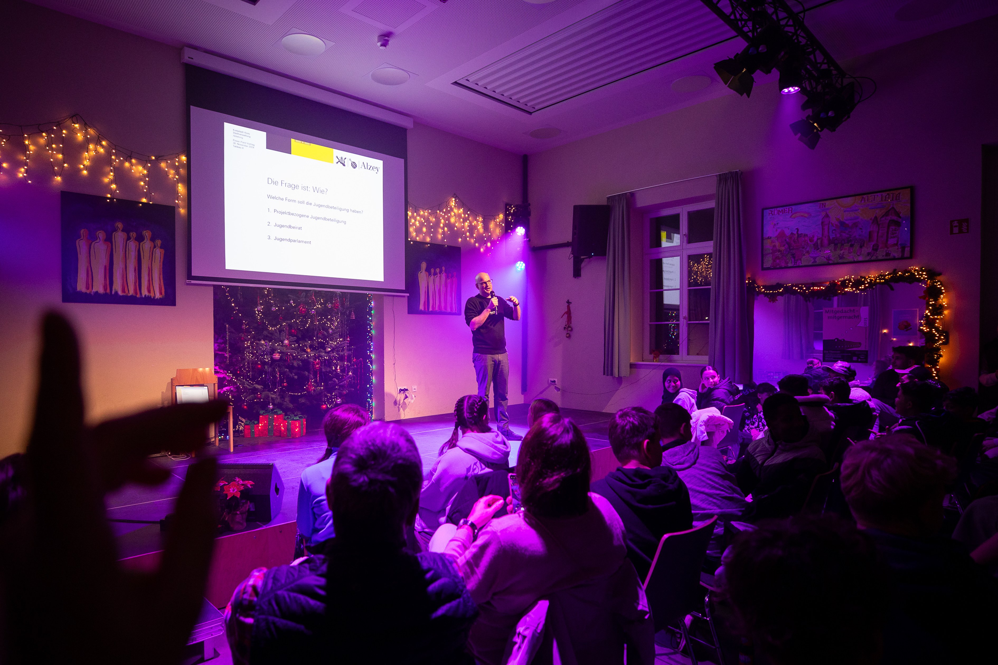 Eine volle Halle, von einem lila Bühnenlicht ausgeleuchtet.