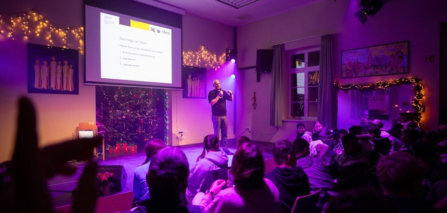Eine volle Halle, von einem lila Bühnenlicht ausgeleuchtet.