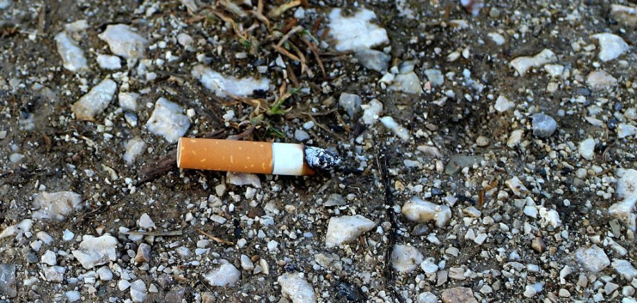 Eine Zigarettenkippe liegt auf der Straße