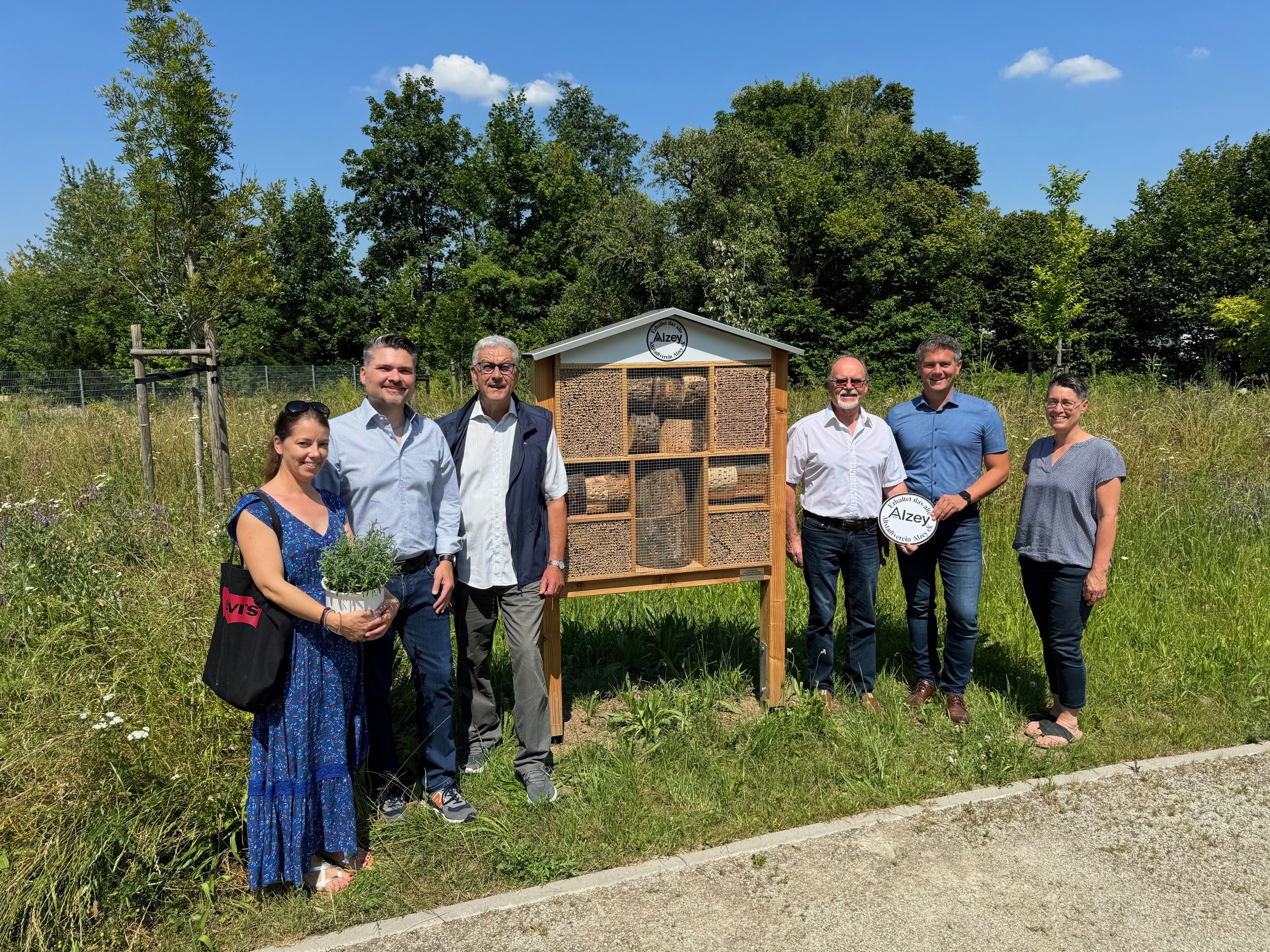 Eine Gruppe von Menschen steht um das Insektenhotel auf dem Alzeyer Friedhof herum.