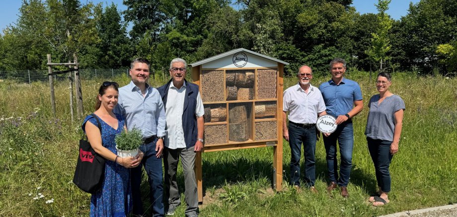 Eine Gruppe von Menschen steht um das Insektenhotel auf dem Alzeyer Friedhof herum.