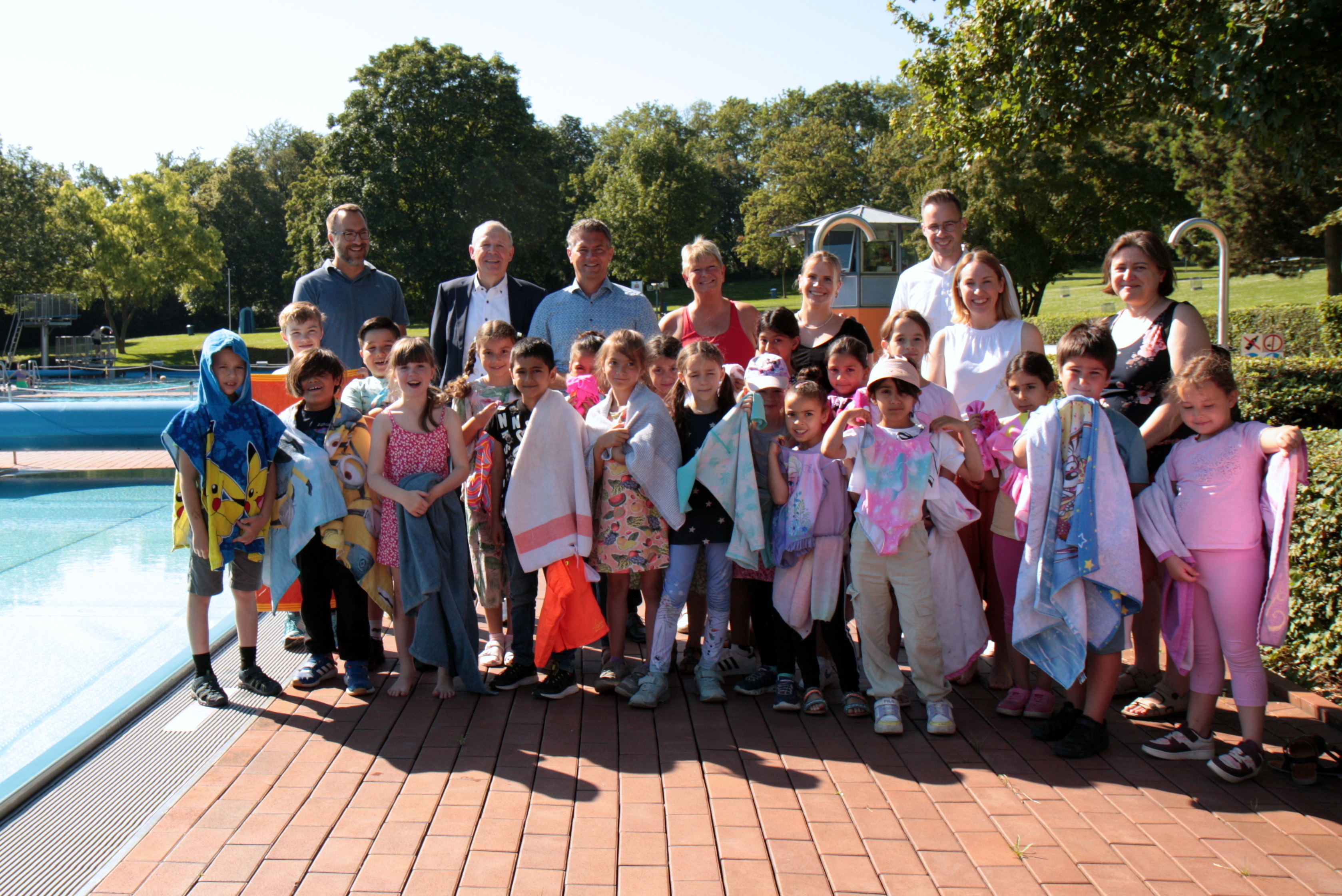 Die Kinder der Nibelungenschule mit Vertretern des Rotary Clubs Alzey stehen am Beckenrand des Schwimmerbeckens im Alzeyer Wartbergbad