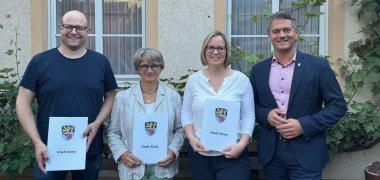Zwei Männer und zwei Frauen stehen mit Urkunden vor dem Gemeindehaus Dautenheims.
