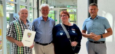 Drei Männer und eine Frau stehen gemeinsam im Foyer des Alzeyer Rathauses.