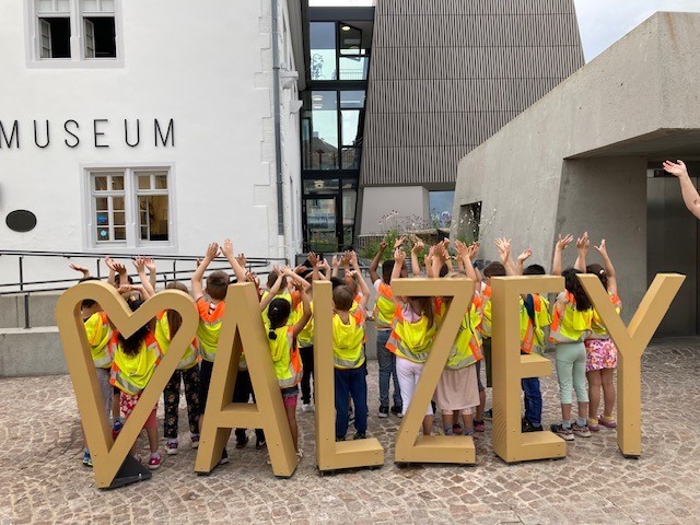 Kinder stehen mit erhobenen Händen hinter dem Alzey Logo am Alzeyer Museum