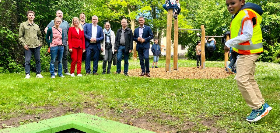 Eine große Gruppe von Personen stehen zwoschen Bodentrampolin und Kletterstangen, an denen die Kinder munter spielen.