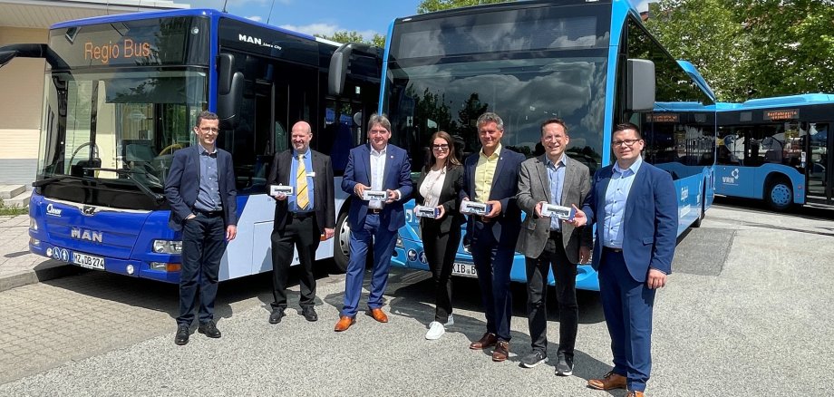 Mehrere Personen stehen vor den blauen Bussen der Verkehrsbetriebe und halten Spielzeugbusse in den Händen.