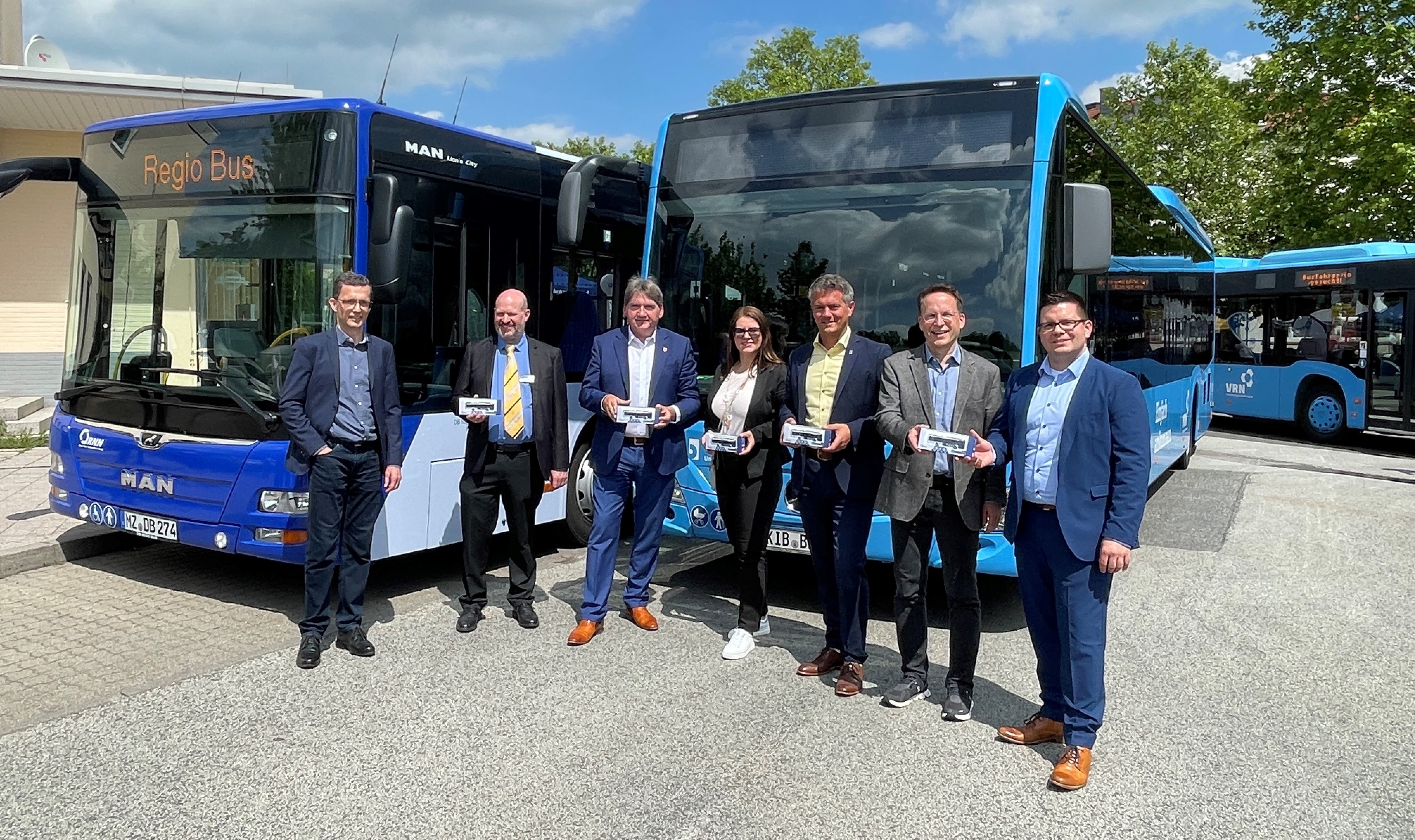 Mehrere Personen stehen vor den blauen Bussen der Verkehrsbetriebe und halten Spielzeugbusse in den Händen.