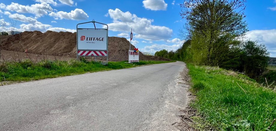 Der Selztalradweg. Im Hintergrund ist ein großer Erdhaufen zu sehen. Rechts des Weges verläuft die Selz.