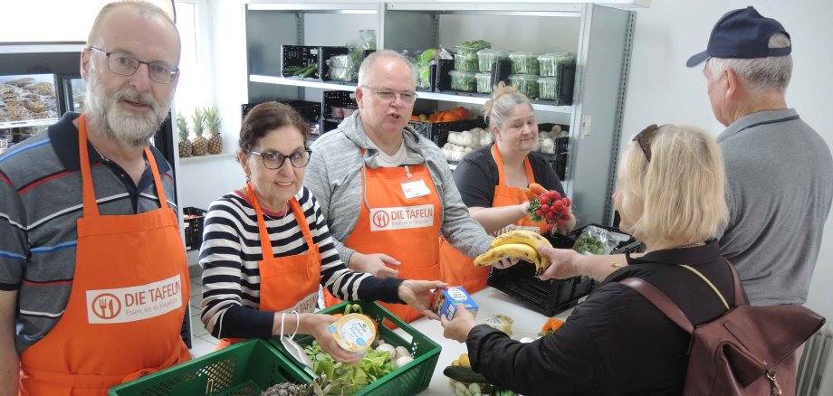 Mitarbeitende der Tafel Alzey geben Lebensmittel an bedürftige Menschen aus.