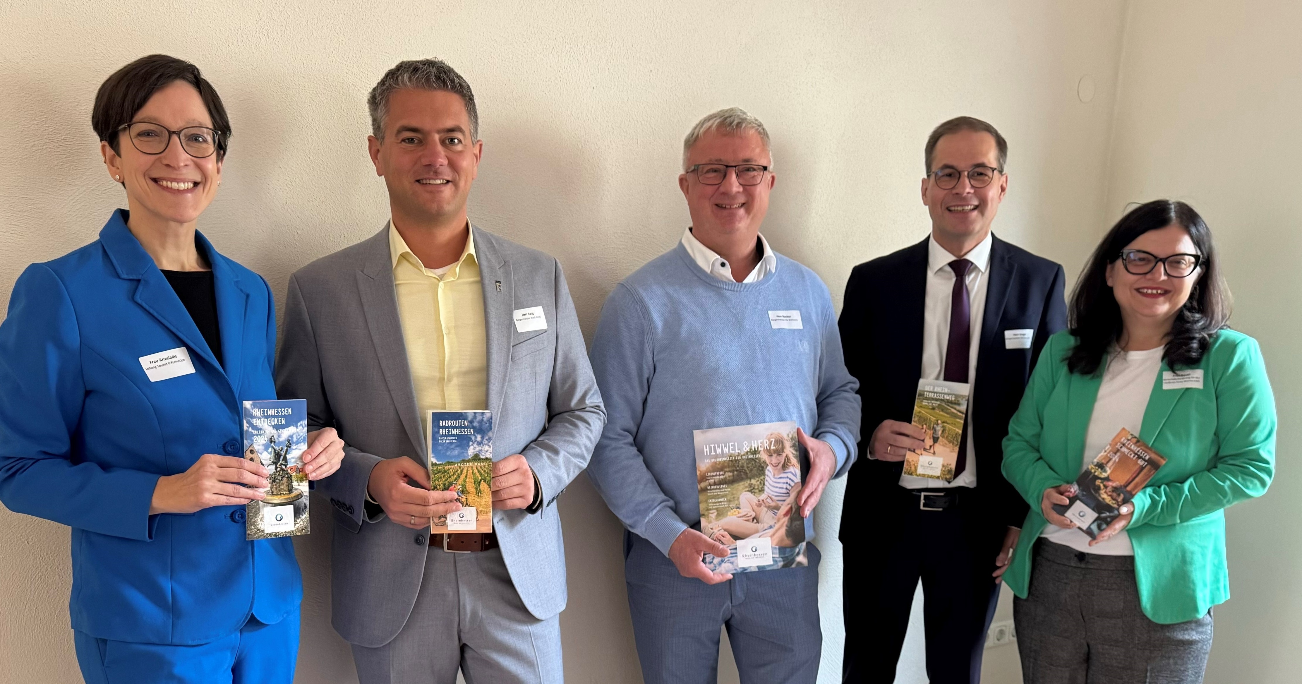 Verschieden Personen stehen nebeneinander und halten Broschüren und Prospekte in der Hand