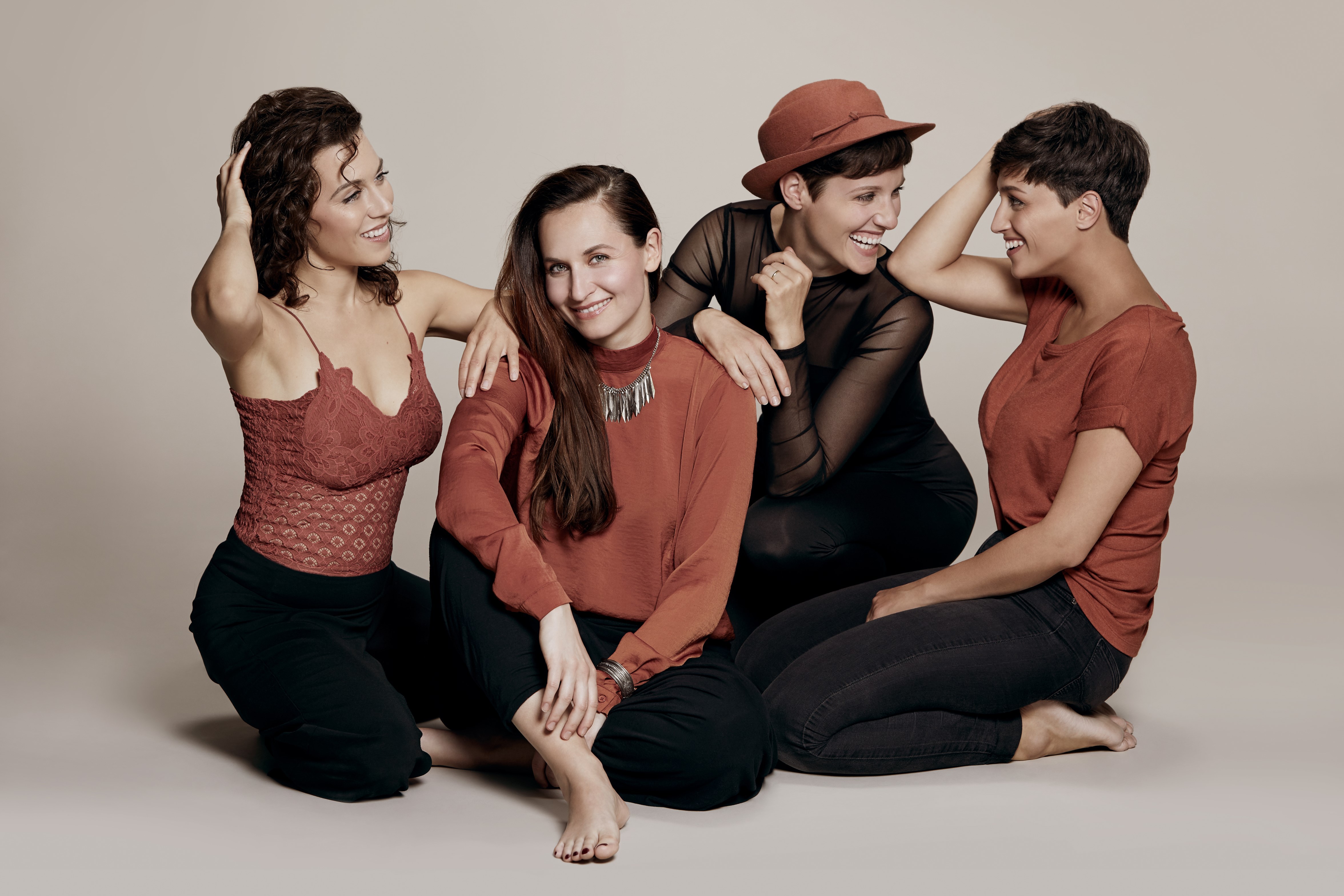 Vier Frauen sitzen auf dem Boden nebeneinander und schauen in die Kamera