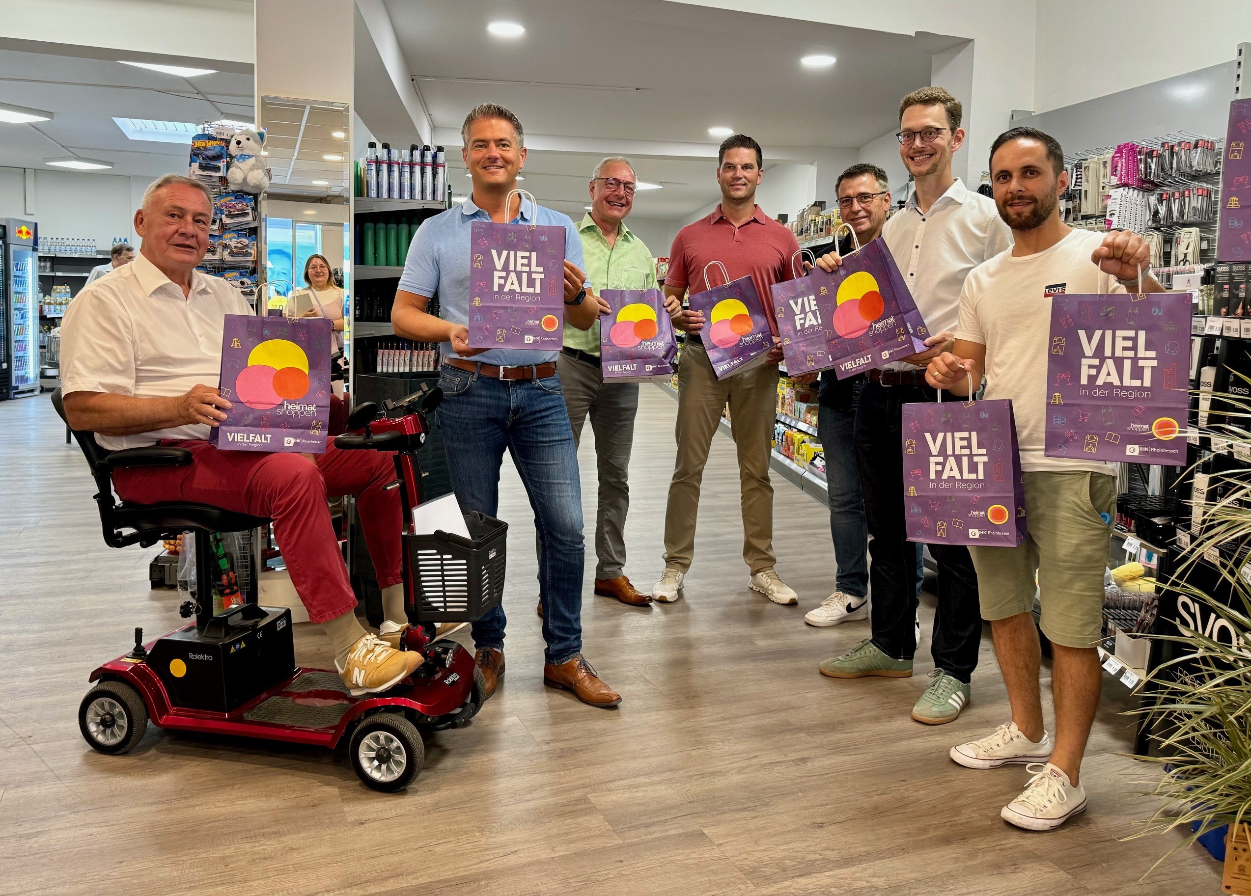 Mehrere Personen halten in einem Supermarkt bunte Papiertüten mit dem Wort Vielfalt hoch