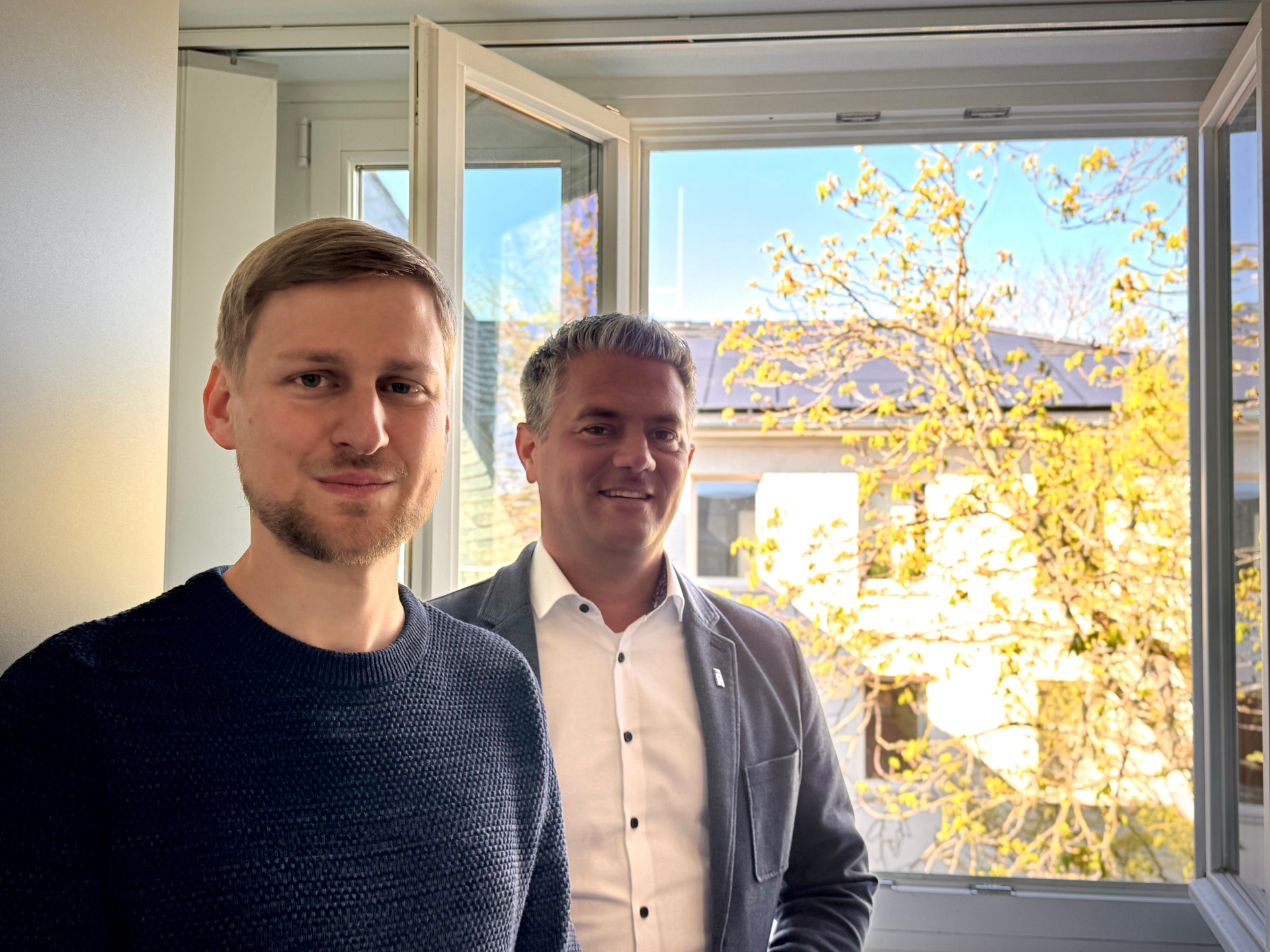 2 Männer am offenem Fenster mit strahlender Sonne