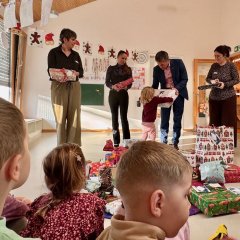 Wunschbaumaktion des Rheinhessen Centers "113 Kinderwünsche" Alzeyer Kita erfüllten Kinder Wünsche. (Zu sehen sind viele verpackte Geschenke Bürgermeister Steffen Jung der einem der anwesenden Kindern ein Geschenk überreicht und die Verantwortlichen für diese Aktion)
