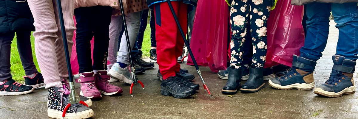 mehrere Beine von Kindern mit Greifzangen beim Müll aufheben