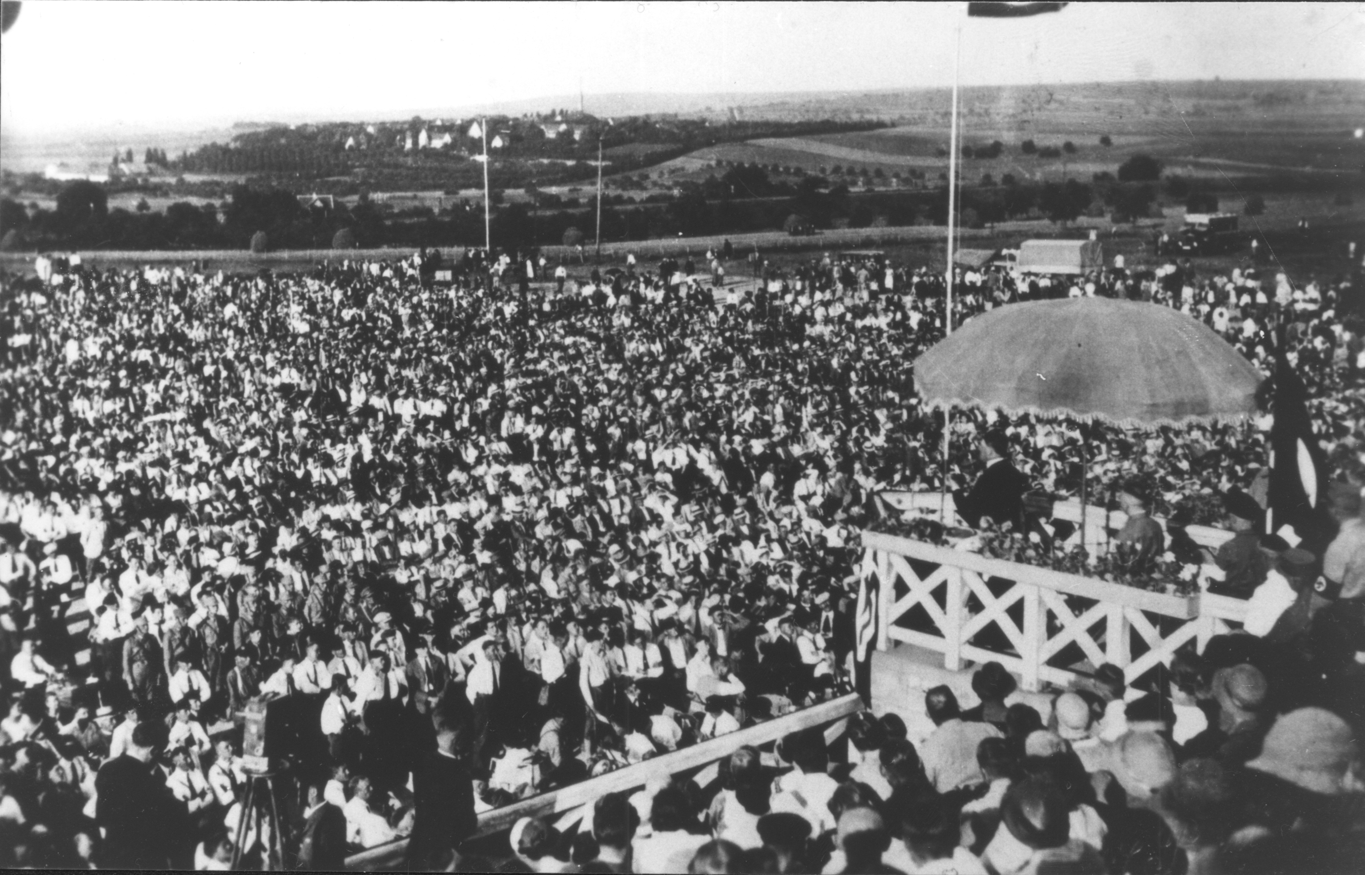 älteres Schwarz-Weiß Bild mit einer Menschenmenge und einer der redet