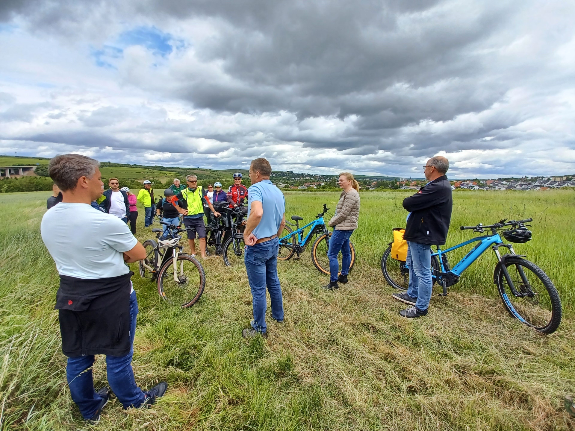 mehrere Personen mit Fahrrädern auf einer Wiese