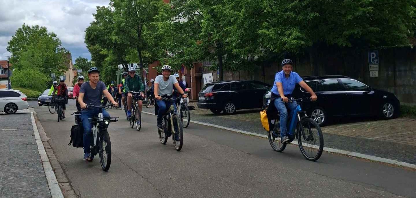 mehrere Personen fahren Fahrrad hinter dem Rathaus auf der Straße